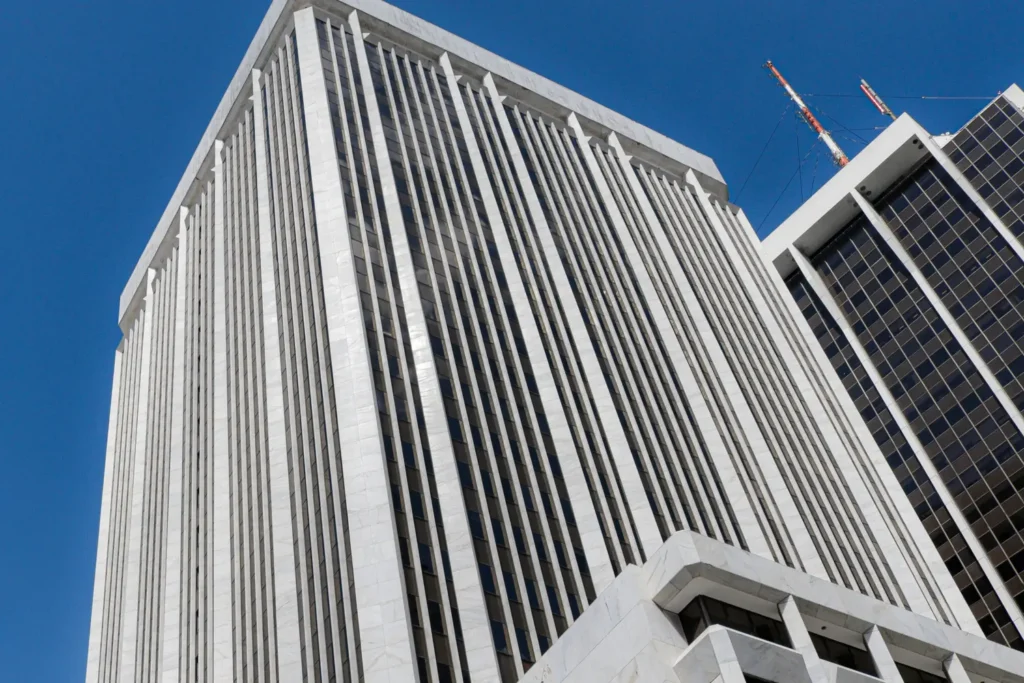 White office tower seen from below against a blue sky